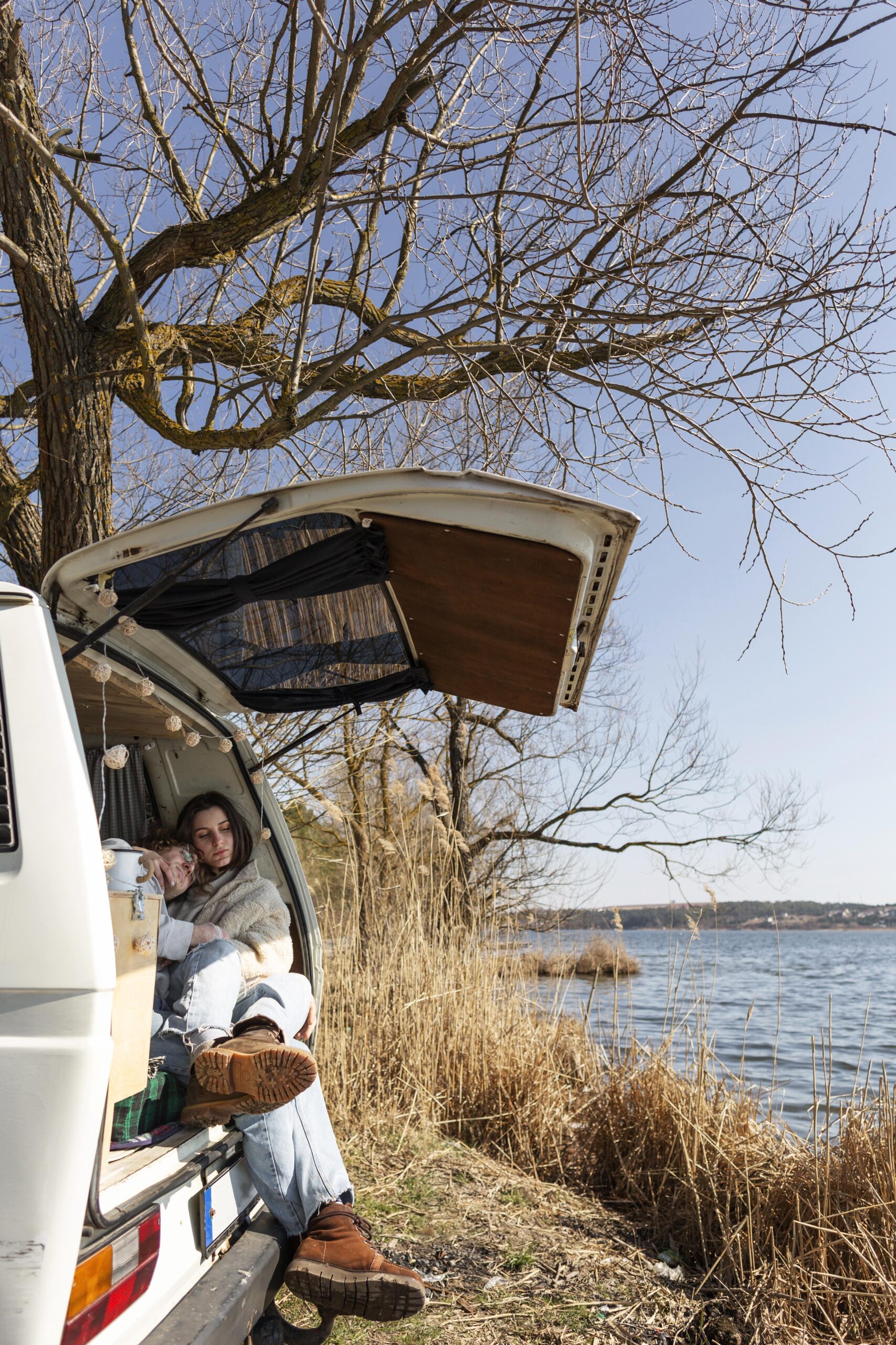 Paar gemütlich im offenen Campervan am See